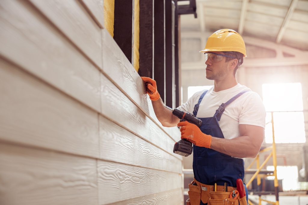 young man installing exterior siding