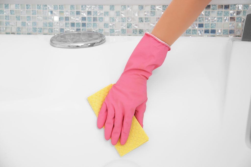 female hand with sponge cleaning a bath
