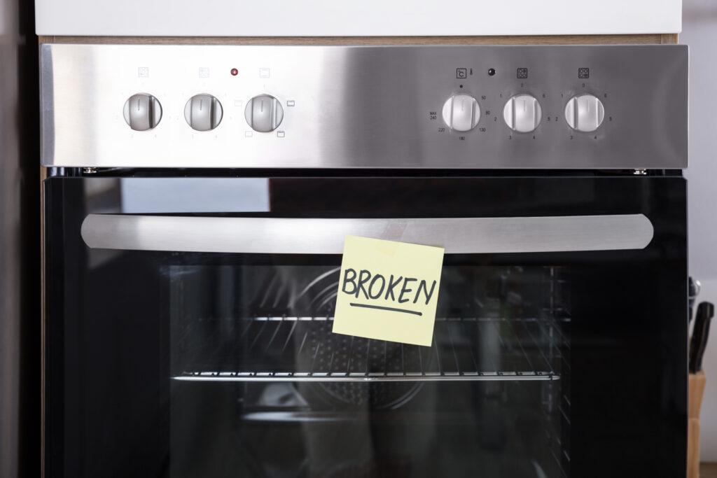 close up of an oven with a sticky note showing broken text