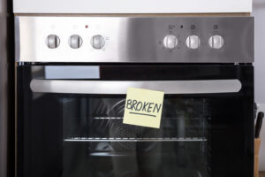 close up of an oven with a sticky note showing broken text