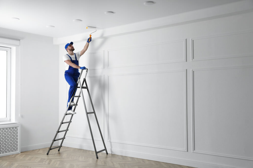 handyman painting ceiling with white dye