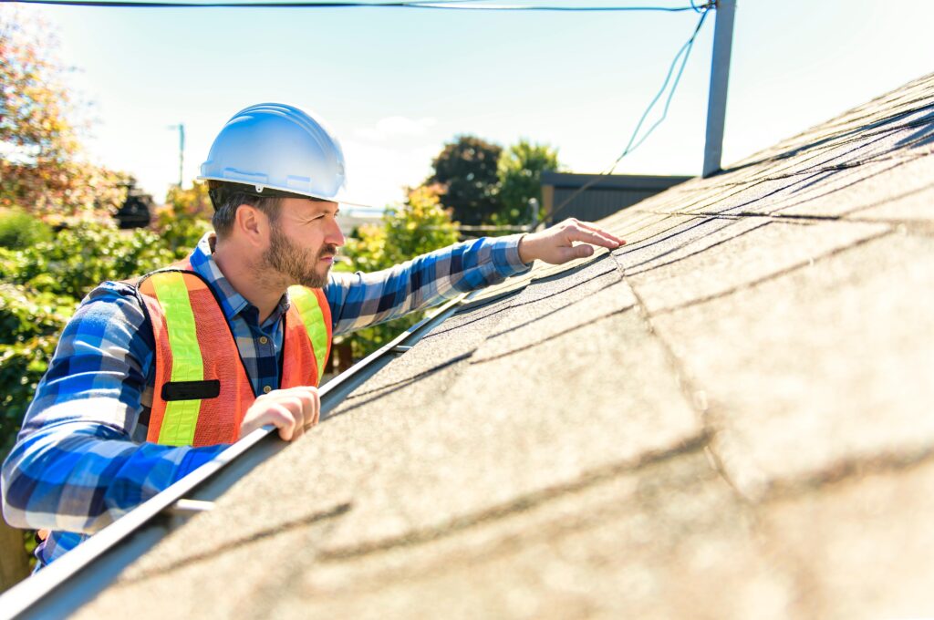 a man with a hard hat inspecting roof of home