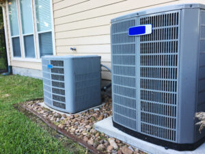 Central air conditioning units beside a house, for home HVAC system installation and maintenance concept.