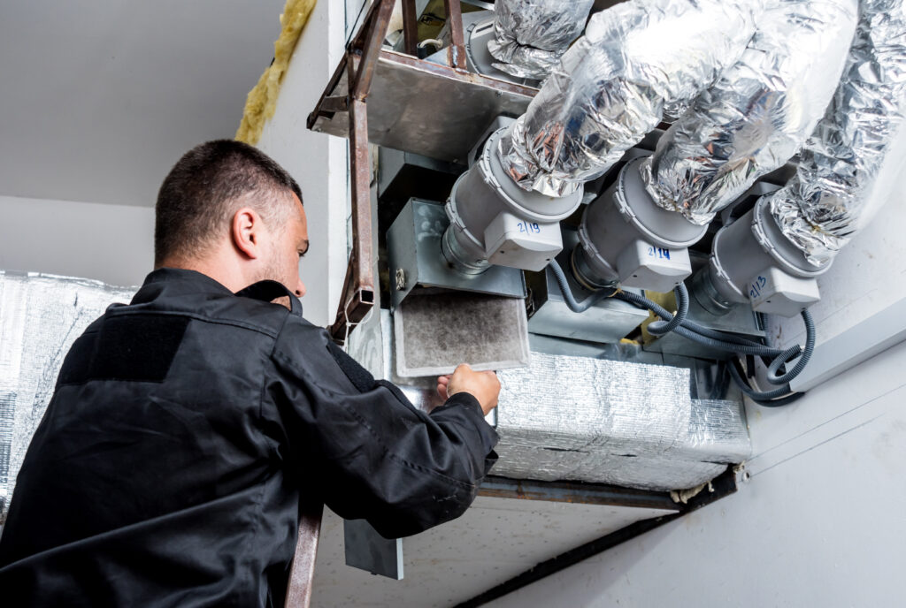 An HVAC professional cleaning the air ducts of a residential HVAC system.