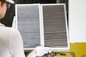 Person holding a new and dirty HVAC filter, demonstrating the importance of regular air filter replacement for indoor air quality.