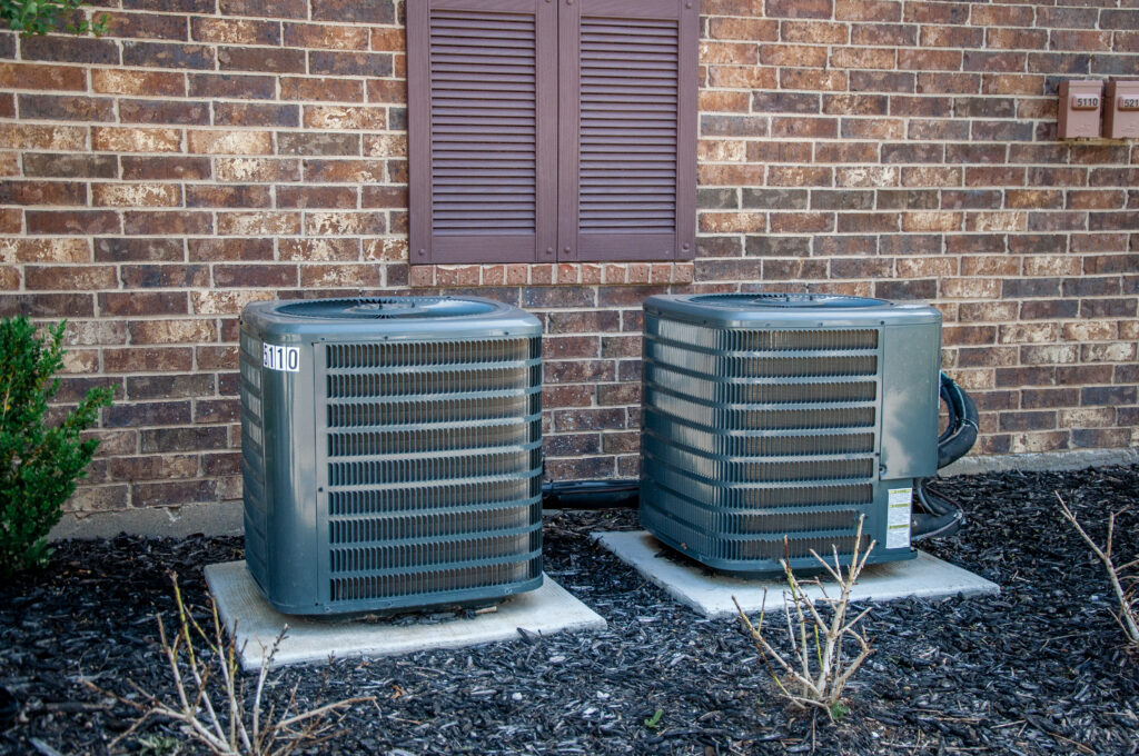 two hvac units in the backyard of a home