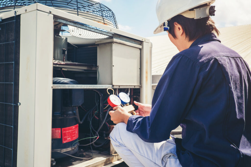 An HVAC technician with the side of an HVAC unit open checking the pressure.