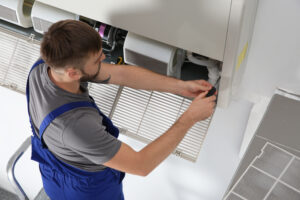 young male technician repairing indoor ac unit