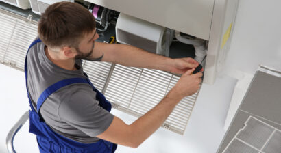 young male technician repairing indoor ac unit