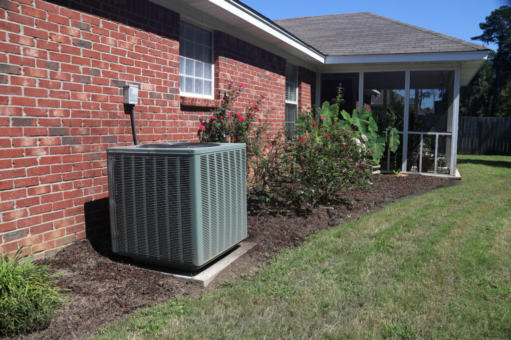 A very large HVAC unit on the side of a brick house.