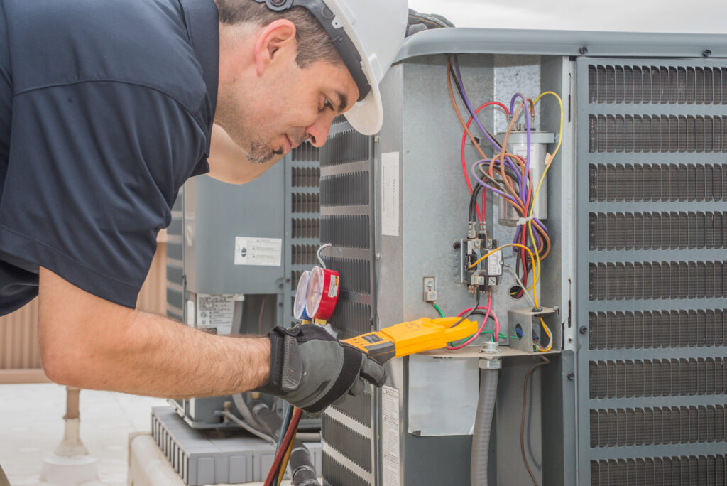 An HVAC technician verifying the electric charge of an HVAC unit