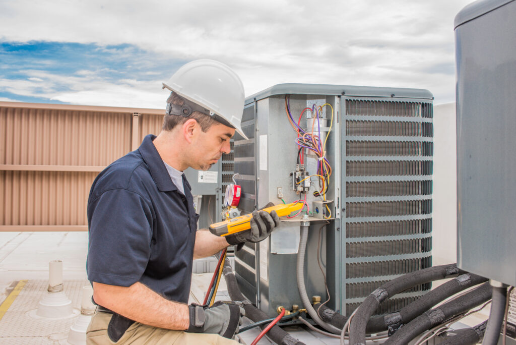 An HVAC technician checking a multimeter to check for the electrical current of an HVAC unit.