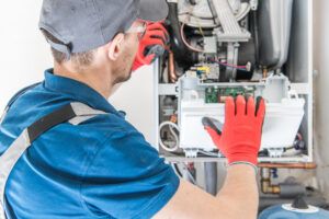 An HVAC technician checking the flame sensor on a furnace.