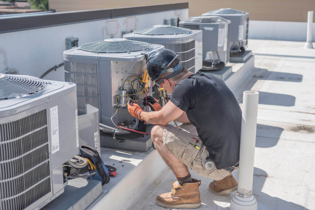 An HVAC technician who has opened up an HVAC unit to check the electrical charge