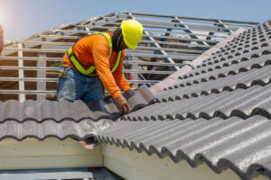 A roofing professional on top of a home replacing a residential roof.