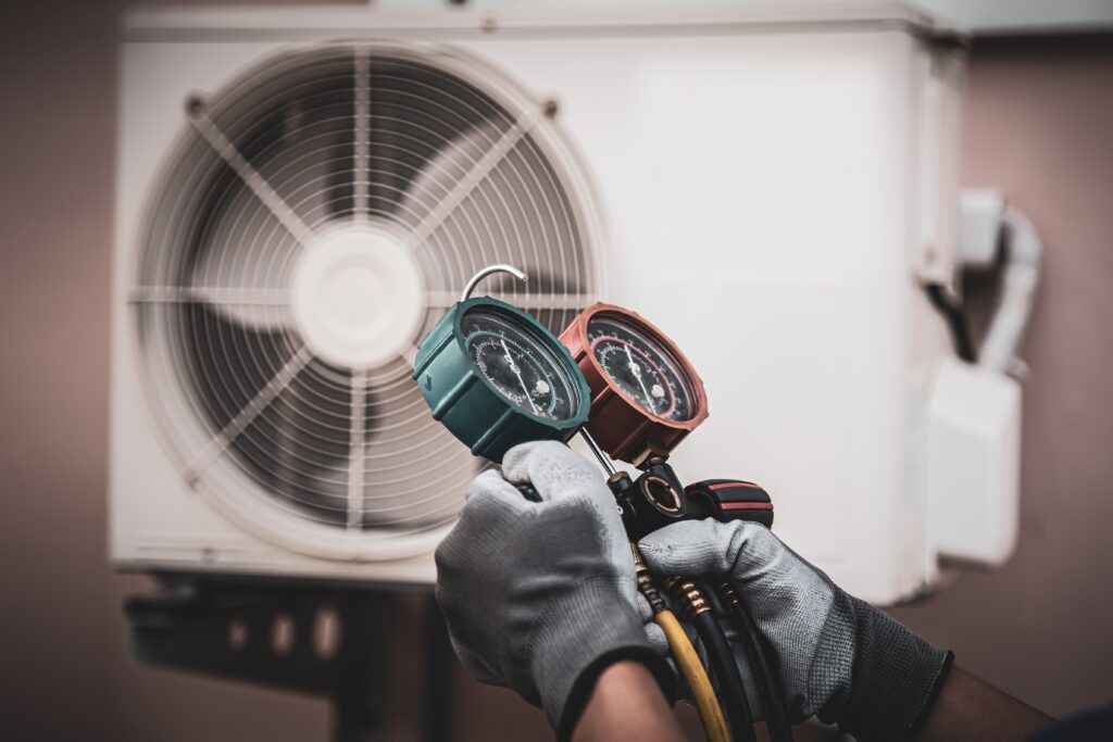 A technician with a manometer in hand to check the pressure on an HVAC unit.