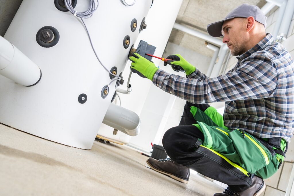 A technician crouched down working on an HVAC unit.