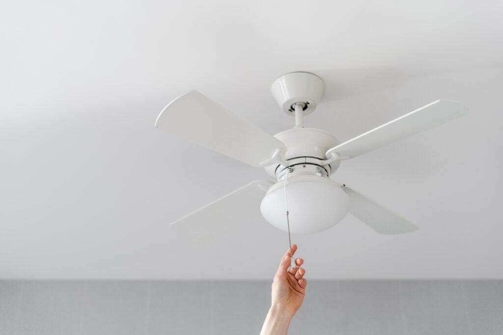 A homeowner turning on a fan by pulling the chain.