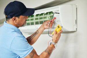 HVAC technician in light blue performing service on hvac syste,.