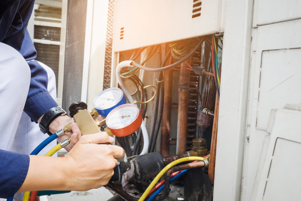 An HVAC technician in front of an opened up HVAC unit checking the pressure.