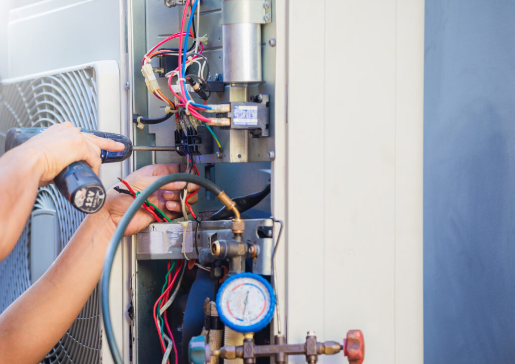 male technician hands using a screwdriver to fix an ac unit