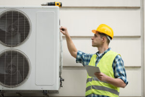hvac technician in a hard hat and vest inspecting a unit