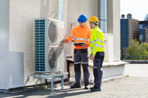 two men checking air conditioning unit