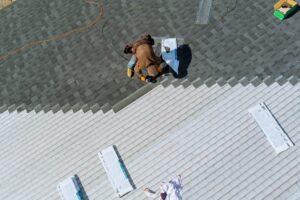 aerial of worker nailing new roof shingles