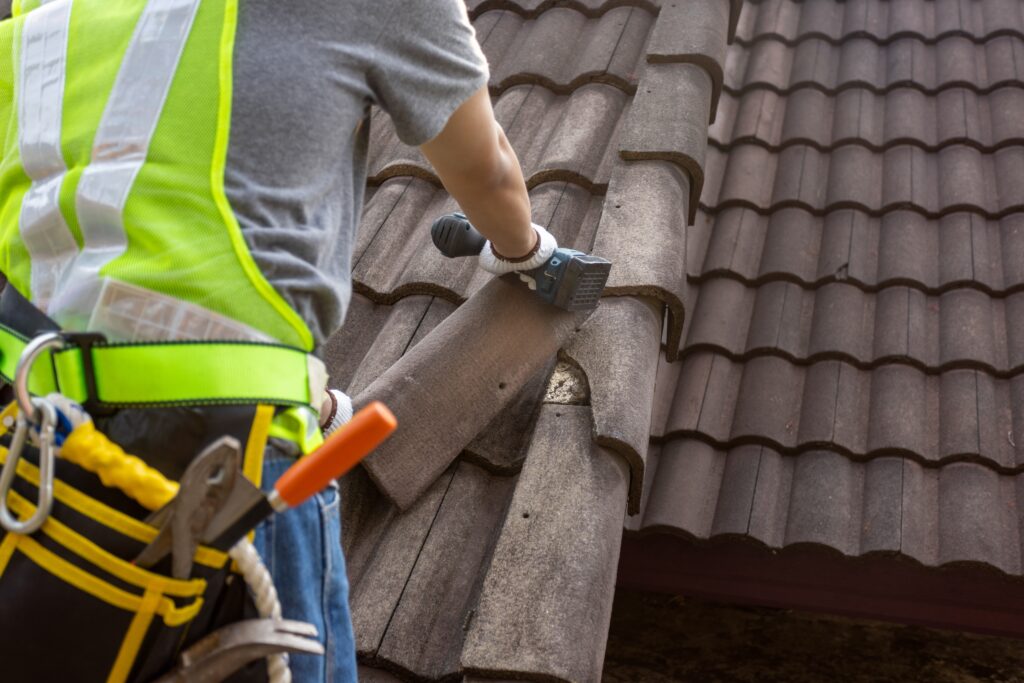 worker replacing old tile on a roof