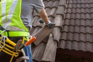 worker replacing old tile on a roof