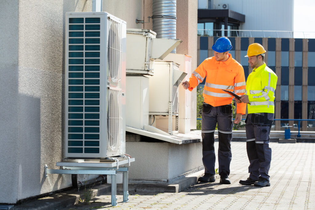 two men wearing safety gear checking hvac system