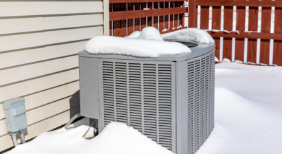 house ac unit covered in snow during winter
