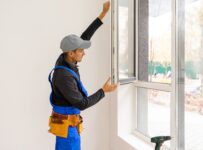 construction worker installing new windows in house