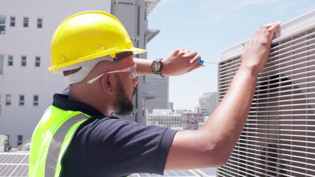 technician using screw driver for ac unit