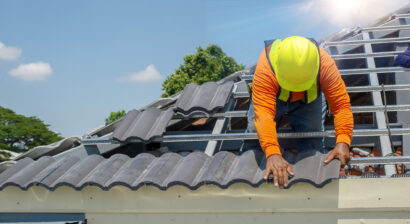 roof repair worker with gloves on replacing tiles