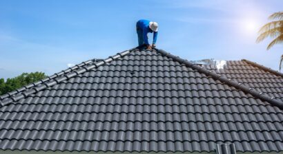 roof repair worker replacing shingles on house