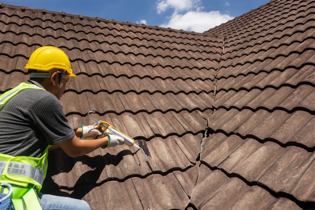 worker using silicone to fix crack in roof