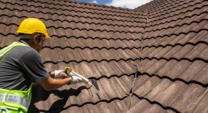 worker using silicone to fix crack in roof