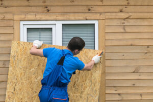 a man obstructs a window with a large piece of wood