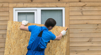 a man obstructs a window with a large piece of wood