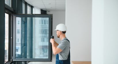 worker in overalls installing or adjusting window