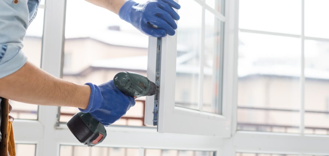 handyman adjusting white window indoors