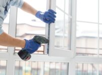 handyman adjusting white window indoors