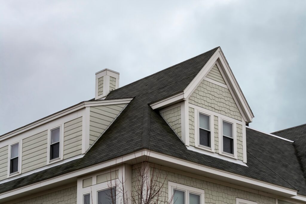 dormer windows and a sloped shingled roof on a home
