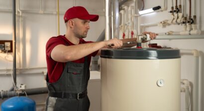 man wearing red shirt fixing a water heater