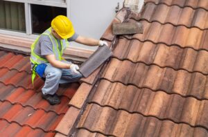 worker fixing eaves and tiles of an old roof