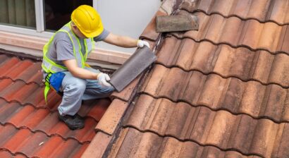 worker fixing eaves and tiles of an old roof