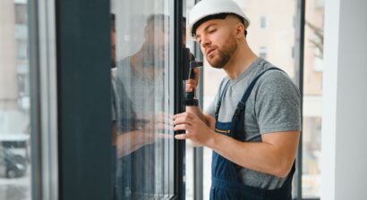 worker in overalls installing or adjusting windows