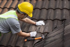 worker replacing tile of old roof