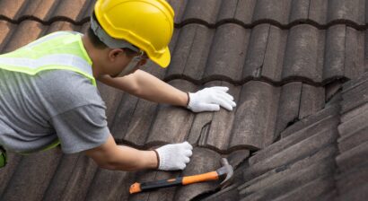 worker replacing tile of old roof